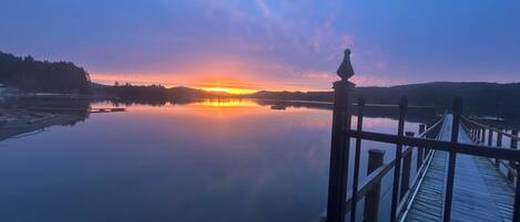 A calm lake at sunset with a wooden dock extending into the water.