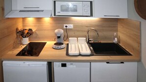Et lille køkken med mikroovn, kaffemaskine, brødrister og vask.