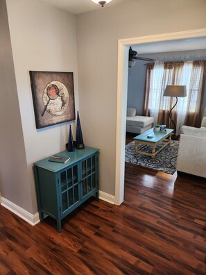 Un salon avec un meuble de couleur turquoise, une œuvre d’art représentant une carte du monde et un tapis à motifs.