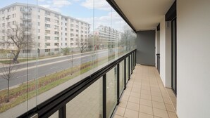 A balcony with a view of a multi-story building and a road.
