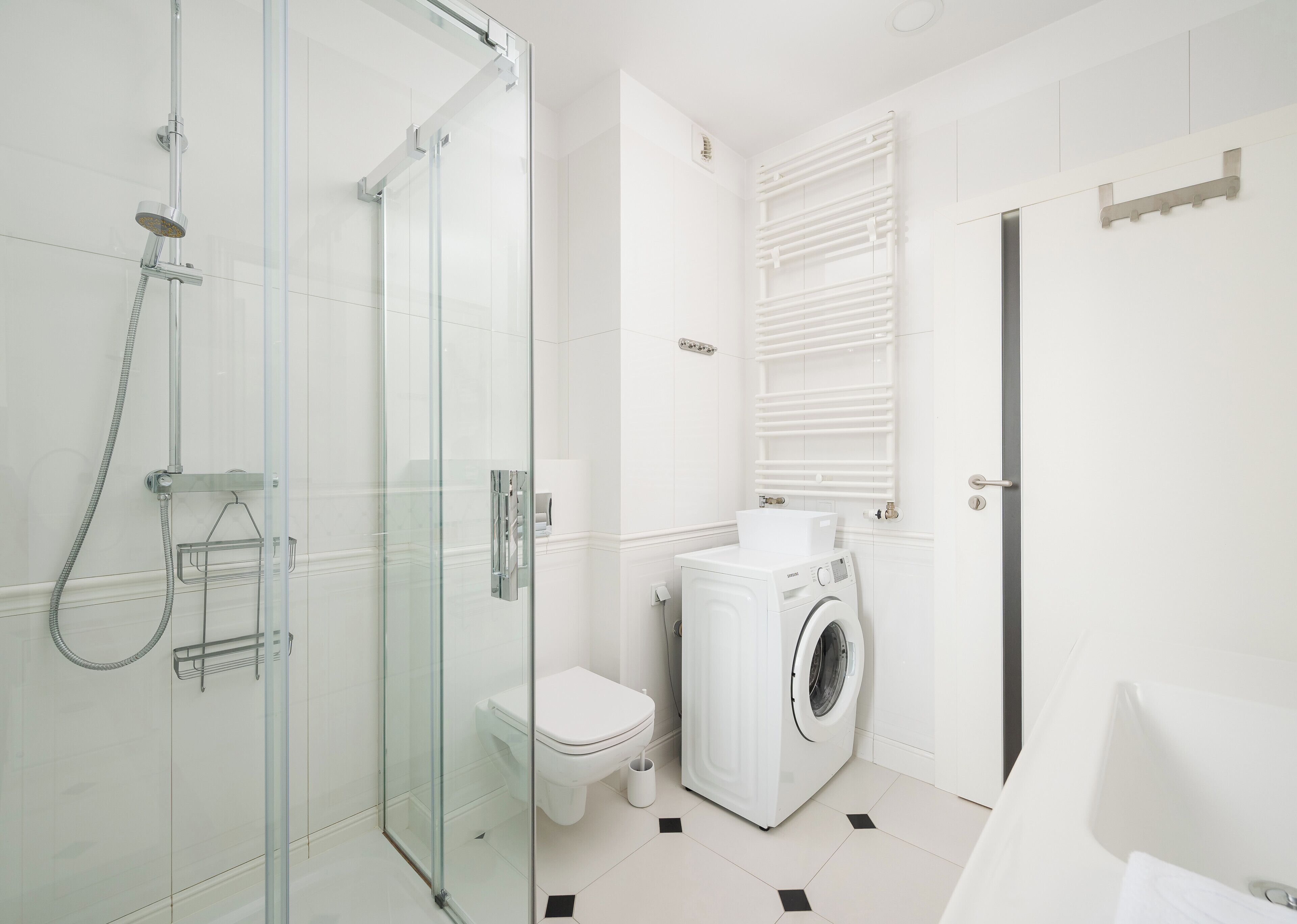 Ein modernes Badezimmer mit Duschkabine, Toilette, Waschmaschine und Handtuchhalter.