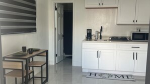 Eine moderne Küche mit weißen Schränken, einer eingebauten Mikrowelle und einer Kaffeemaschine.