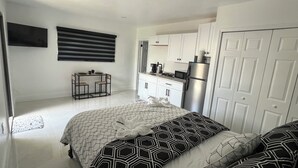 Ein kleines Zimmer mit einem Bett, einem Tisch und einer Küchenzeile.