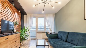 Un salon moderne avec un téléviseur, un canapé, une table basse et une plante.