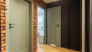 Un couloir avec deux portes, l’une donnant sur un mur décoré de briques apparentes et l’autre sur un mur uni.