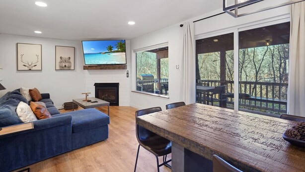 Una sala de estar moderna con un sofá azul, una mesa de comedor de madera y un televisor montado en la pared.