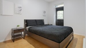 Un dormitorio moderno con una cama, mesita de noche y una planta pequeña.