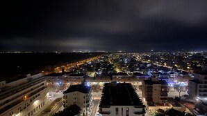 A nighttime cityscape with a prominent building featuring a central atrium and multiple balconies. - WELCS APARTAMENTO 190 EMP cerca del mar (Empuriabrava)