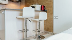 A modern kitchen with two white bar stools, a microwave, and a red kettle on a wooden countertop. - WELCS APARTAMENTO 190 EMP cerca del mar (Empuriabrava)
