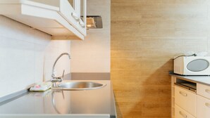 A modern kitchen with a stainless steel sink, a microwave, and wooden cabinetry. - WELCS APARTAMENTO 190 EMP cerca del mar (Empuriabrava)
