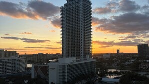 A high-rise hotel with a view of the sunset over a cityscape.