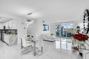 A modern living space with a kitchen, dining area, and a balcony with a city view.