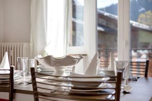 A dining table set with plates, glasses, and a white bowl.