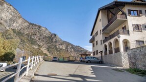 Un edificio con fachada de piedra, varios balcones y montañas al fondo.