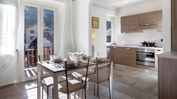 Una cocina moderna con armarios de madera, horno empotrado y comedor con mesa y sillas.