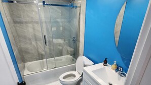 A modern bathroom with a glass-enclosed shower, a white toilet, and a sink with a mirror. - Homely, cozy, spacious quiet basement apartment in a lovely neighborhood.  (Thamesford)