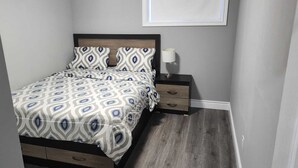 A bedroom with a bed, nightstands, a lamp, and a window. - Homely, cozy, spacious quiet basement apartment in a lovely neighborhood.  (Thamesford)