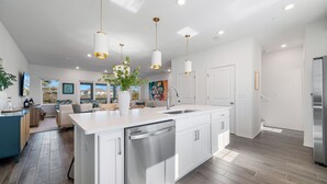 A modern kitchen with white cabinetry, stainless steel appliances, and pendant lighting.
