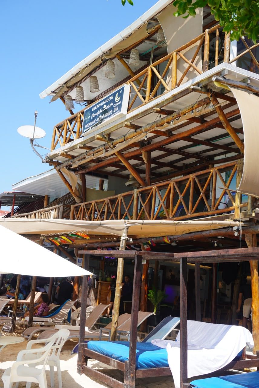 Een strandbar met een bord waarop 'BIENVENIDOS' en 'AQUA SALSA BAR' staat.