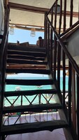 Una escalera de madera que lleva a un balcón con vistas al mar.