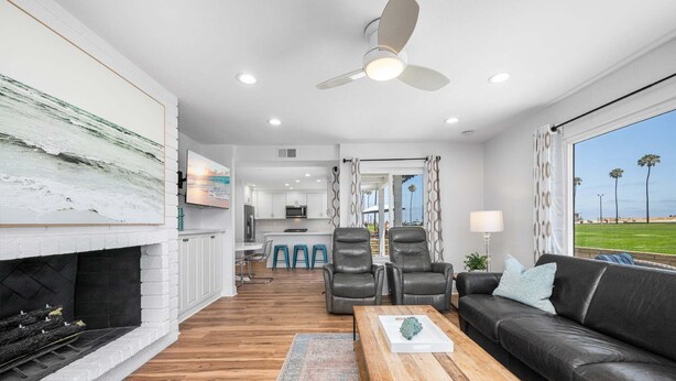 A modern living room with a fireplace, a sofa, a coffee table, and a view of the outdoors. - Beachside Oasis in Newport Beach – Steps to Balboa Park, Pier, and The Fun Zone! (Newport Beach)
