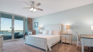 A bedroom with a bed, two bedside tables, a chair, a desk, and a ceiling fan.