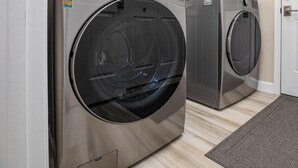 A laundry room with two front-loading LG washing machines, a window above, and a door to the right. - Pine Cone Paradise - escape to luxury! (Mount Jackson)