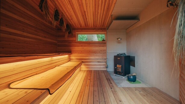 A wooden cabin interior with a bench, a fireplace, and a window. - NEGURA (Ogimi)