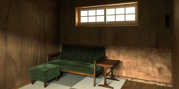 A room with a green sofa, a small wooden table, and a window with a grid pattern. - NEGURA (Ogimi)