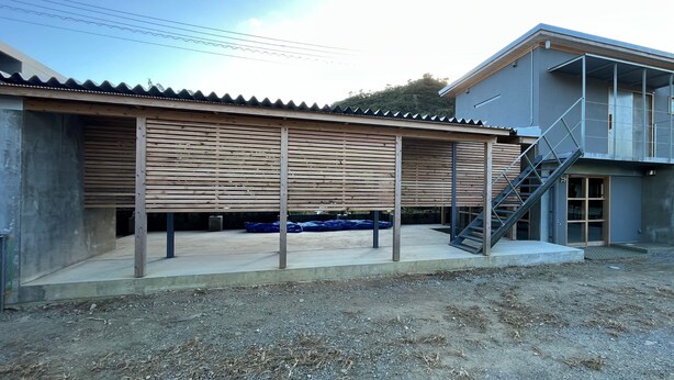 A modern building with a covered area, a staircase, and a concrete foundation. - NEGURA (Ogimi)