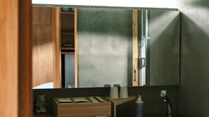 A bathroom with a wooden vanity, a mirror, and a bottle of hand soap. - NEGURA (Ogimi)