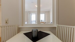 Una habitación de hotel con un ventanal grande, un radiador y una taza de metal sobre un felpudo.