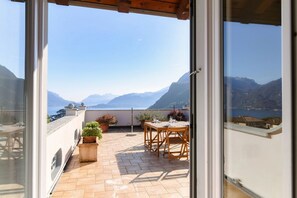A balcony with a table and chairs, potted plants, and a view of mountains and the sea. - Villa Viviana - MyHomeinComo (Menaggio)