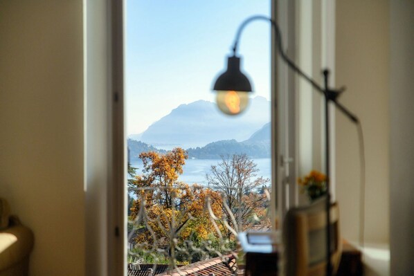 A view through a window with a lamp, a mountain, and trees in the background.