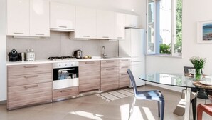 Een moderne keuken met witte kastjes, een glazen eettafel en uitzicht op het omliggende landschap.
