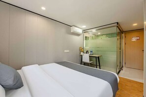 Ein Hotelzimmer mit Bett, Schreibtisch und Duschbereich.