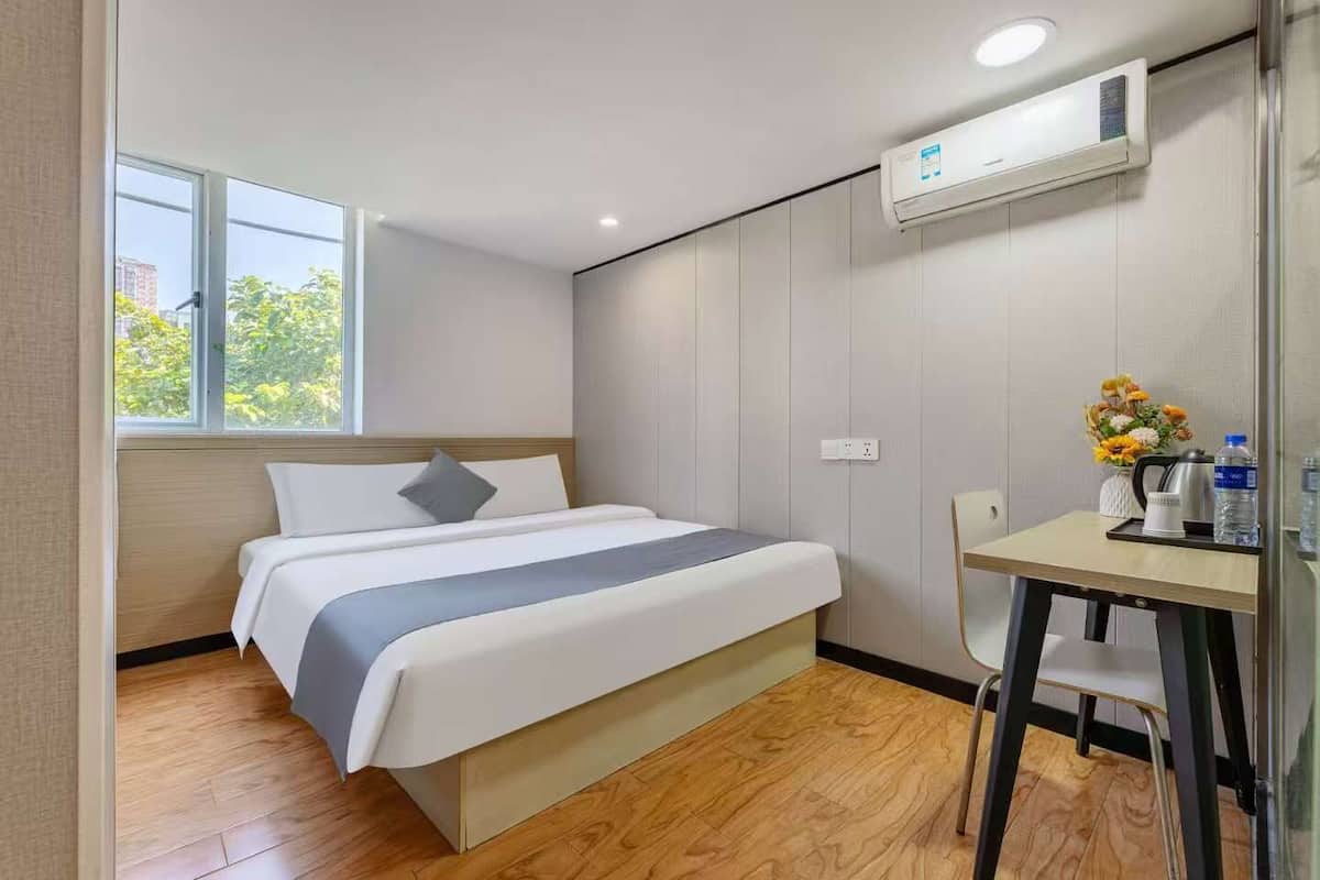 A modern hotel room with a bed, a desk, and a window.