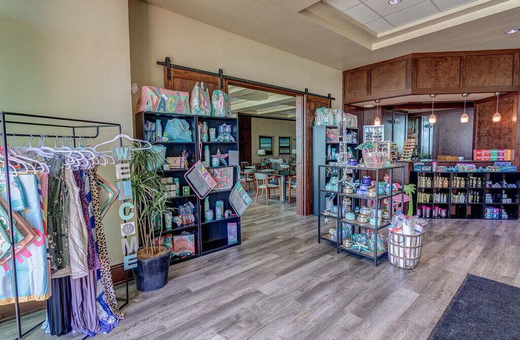 Une boutique proposant des vêtements présentés sur des portants, des étagères remplies d’objets décoratifs et une variété de produits exposés.