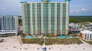 Un hotel de gran altura con varios balcones, una zona de piscina y vista al mar.