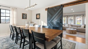 A dining area with a wooden table and chairs, a chandelier, and a herringbone-patterned wall. - Surreal Serenity Escape wIth Game Room, Pool & Spa (La Mesa)