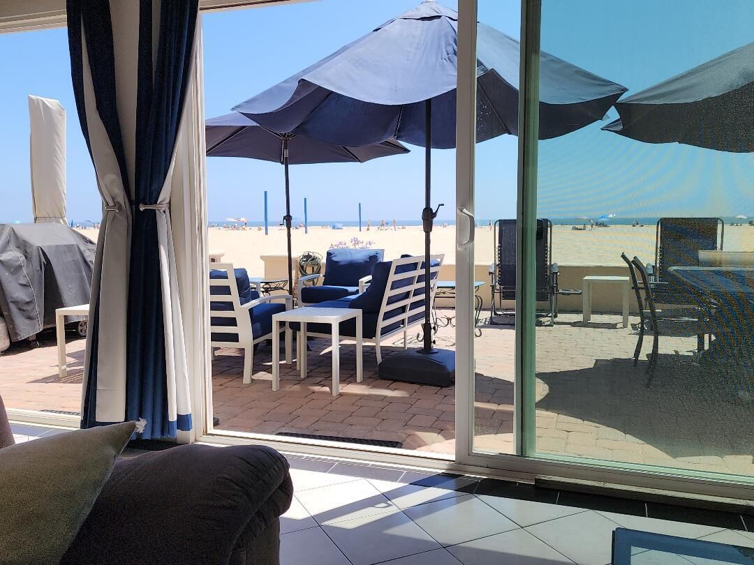 A patio area with outdoor seating, umbrellas, and a view of the beach.
