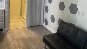 A modern room with a wooden floor, a black sofa, and a hexagonal patterned wall.