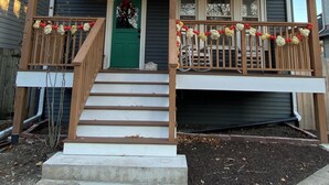 A two-story house with a front porch, a green door, and a balcony with railings.