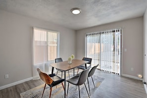 A dining area with a wooden table, six chairs, and a vase with flowers. - Midcentury McMansion on 1 acre lot with Palm trees view (Sacramento)