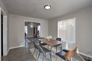 A dining area with a wooden table, six chairs, and a vase of flowers. - Midcentury McMansion on 1 acre lot with Palm trees view (Sacramento)