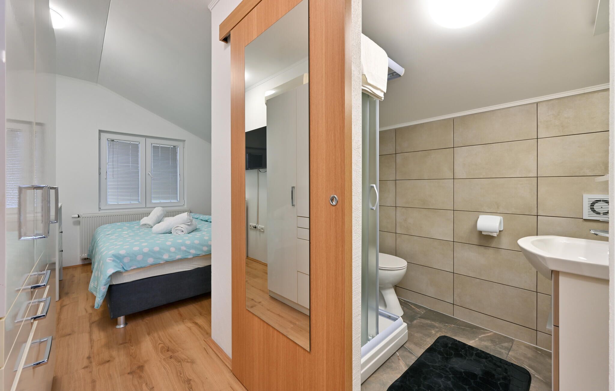 Un dormitorio con cama, un baño con inodoro y lavamanos, y una zona de ducha.