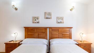 Una cama doble con cabecera de madera, dos mesitas de noche con lámparas y tres lámparas fijadas a la pared.