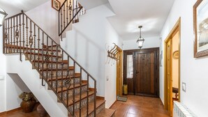 Una escalera con barandillas de metal decoradas, una puerta de madera y un piso de baldosas.