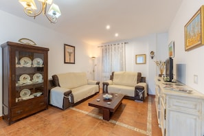 A living room with two sofas, a coffee table, a cabinet with dishes, a TV, and a painting on the wall.