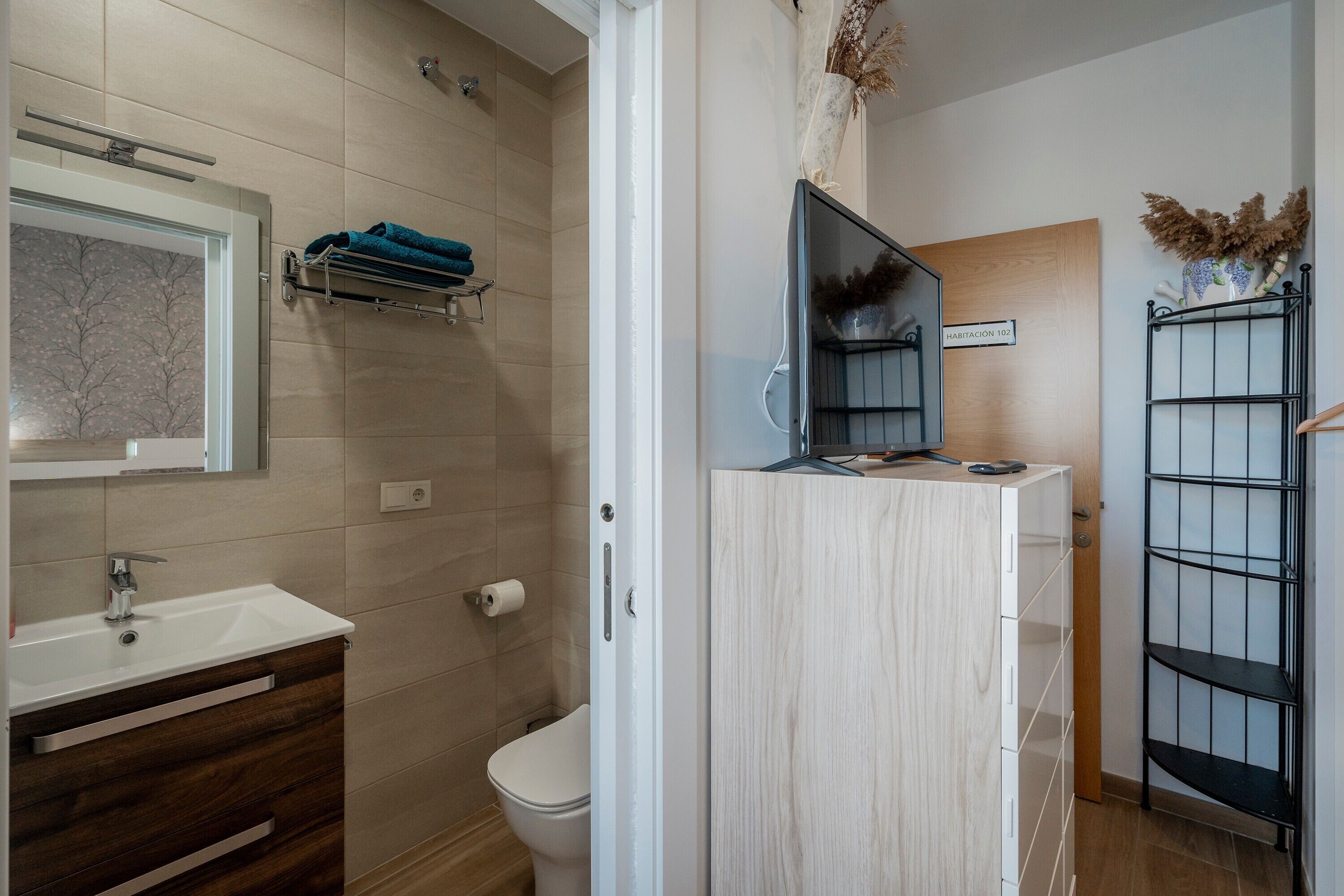 Een badkamer met een wit wastafel, een spiegel, een toilet en een douchegedeelte.